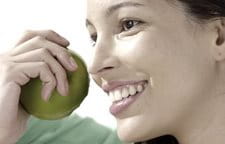 Người phụ nữ đang mỉm cười và cầm một trái táo trên tay.