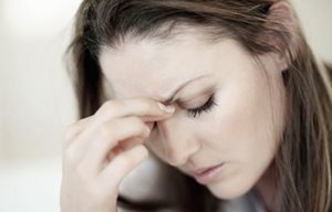 Hình ảnh người phụ nữ đang nhìn xuống, với tư thế mệ mỏi- tay cô ấy đang sờ trán