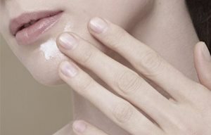 Người phụ nữ đang bôi kem lên cằm của cô ấy