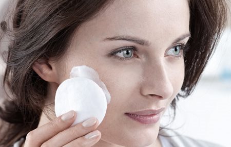 Hình cảnh cô gái đang dùng bông tẩy trang thoa kem dưỡng da lên mặt